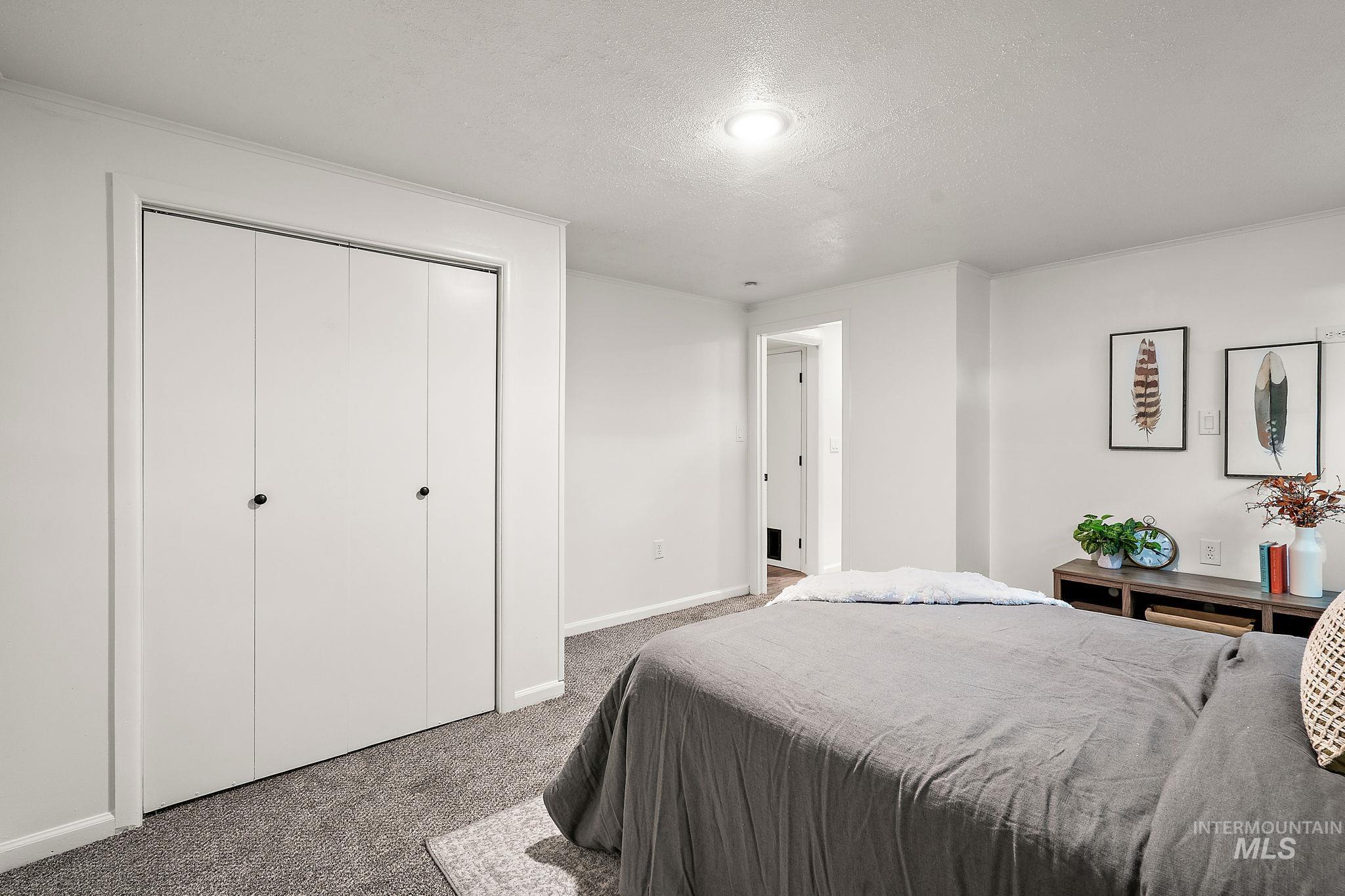 Carpeted bedroom featuring a textured ceiling and a closet