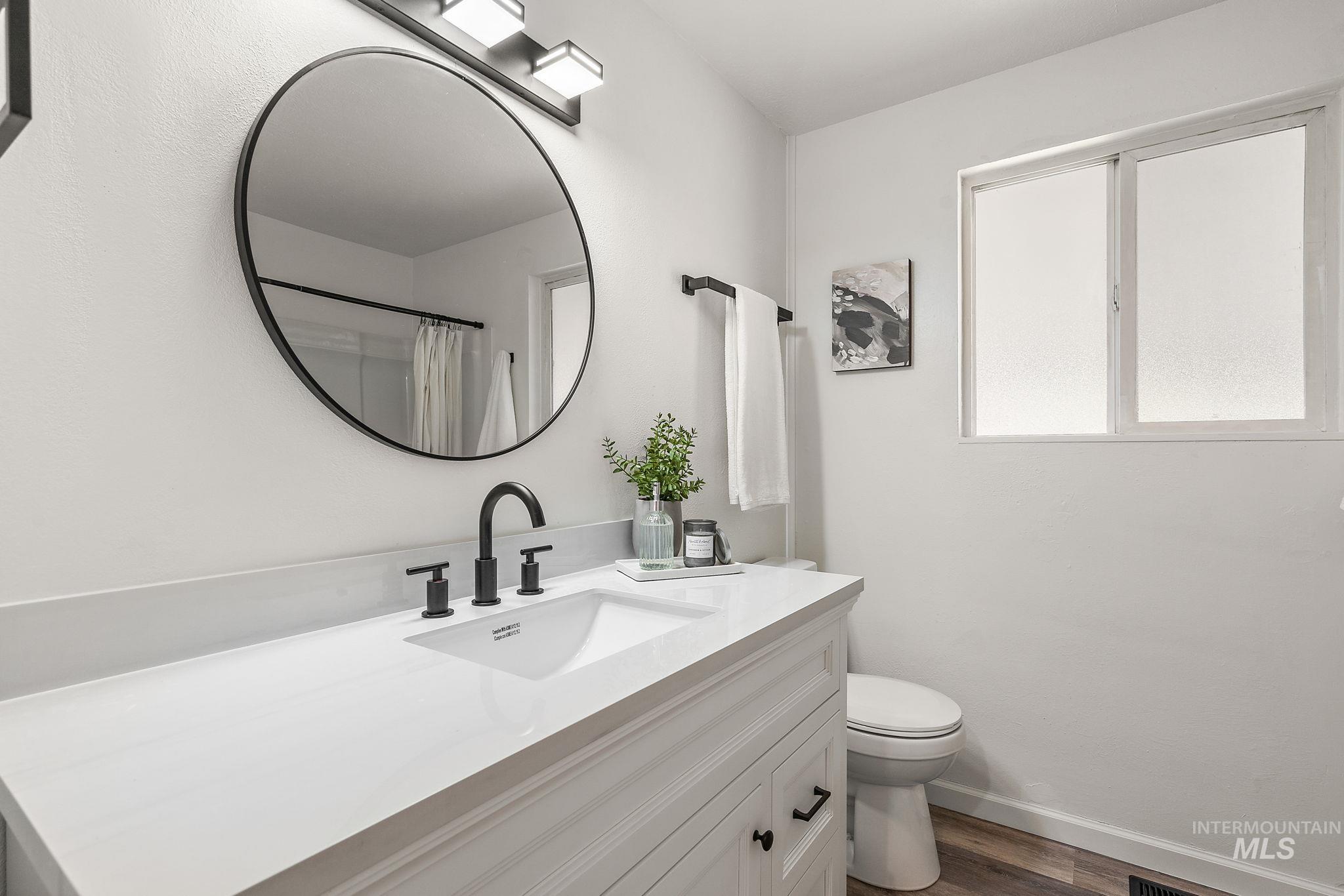 Full bathroom with vanity, dark wood-style floors, and a shower with shower curtain