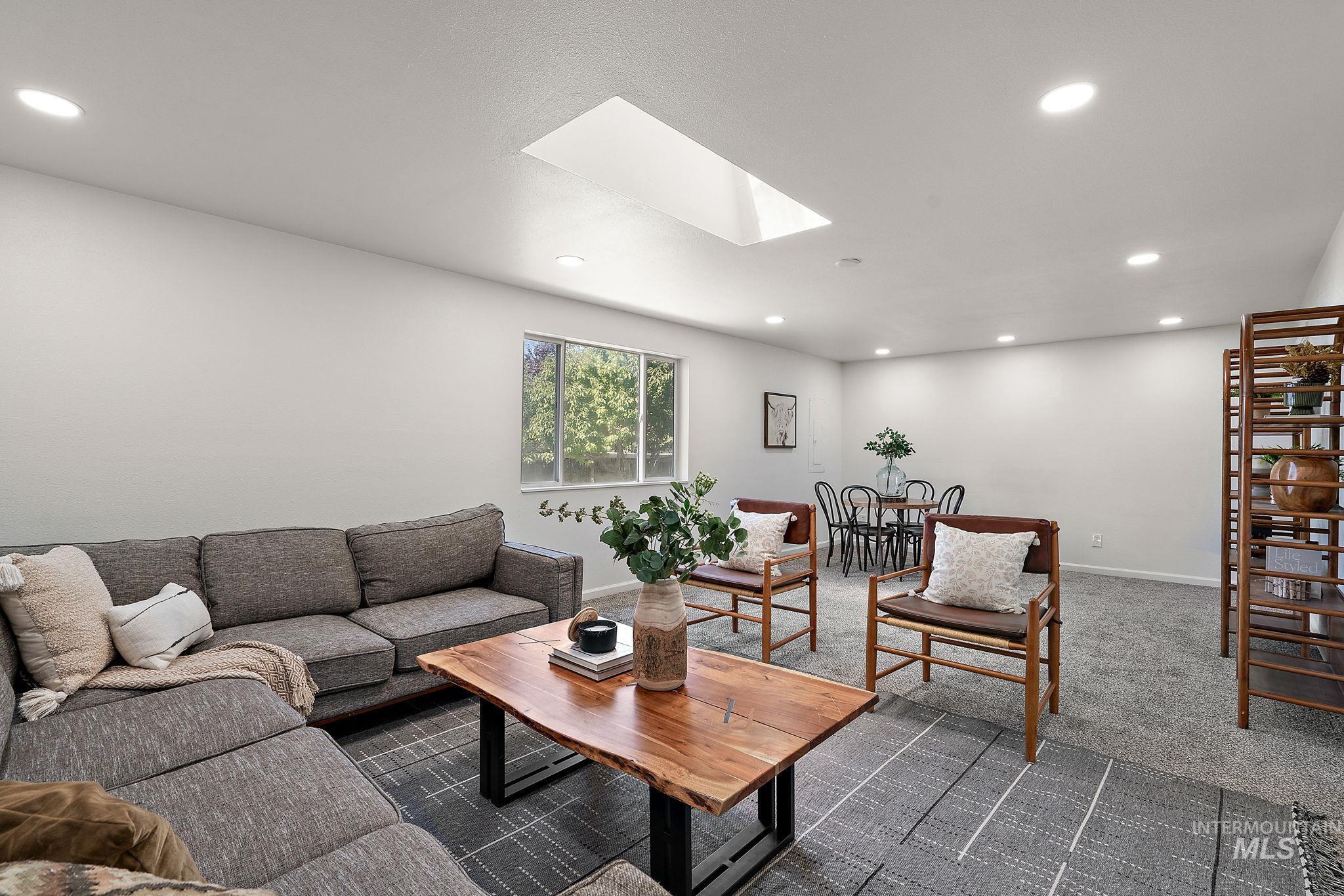 Living area with recessed lighting, a skylight, and dark colored carpet