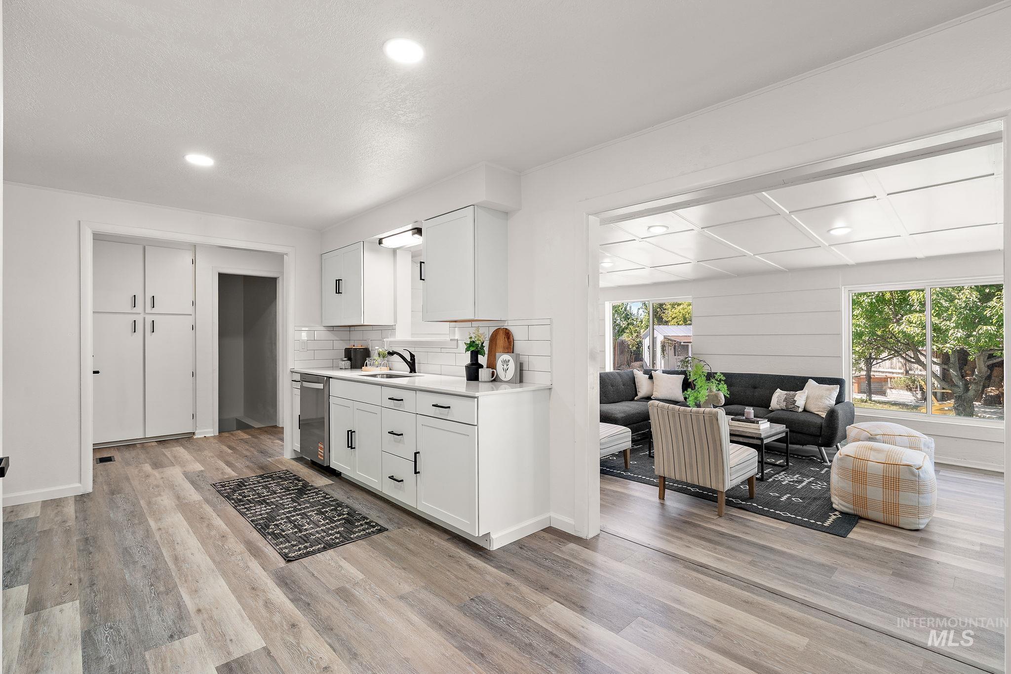 Kitchen featuring recessed lighting, white cabinets, tasteful backsplash, light wood-type flooring, and stainless steel dishwasher