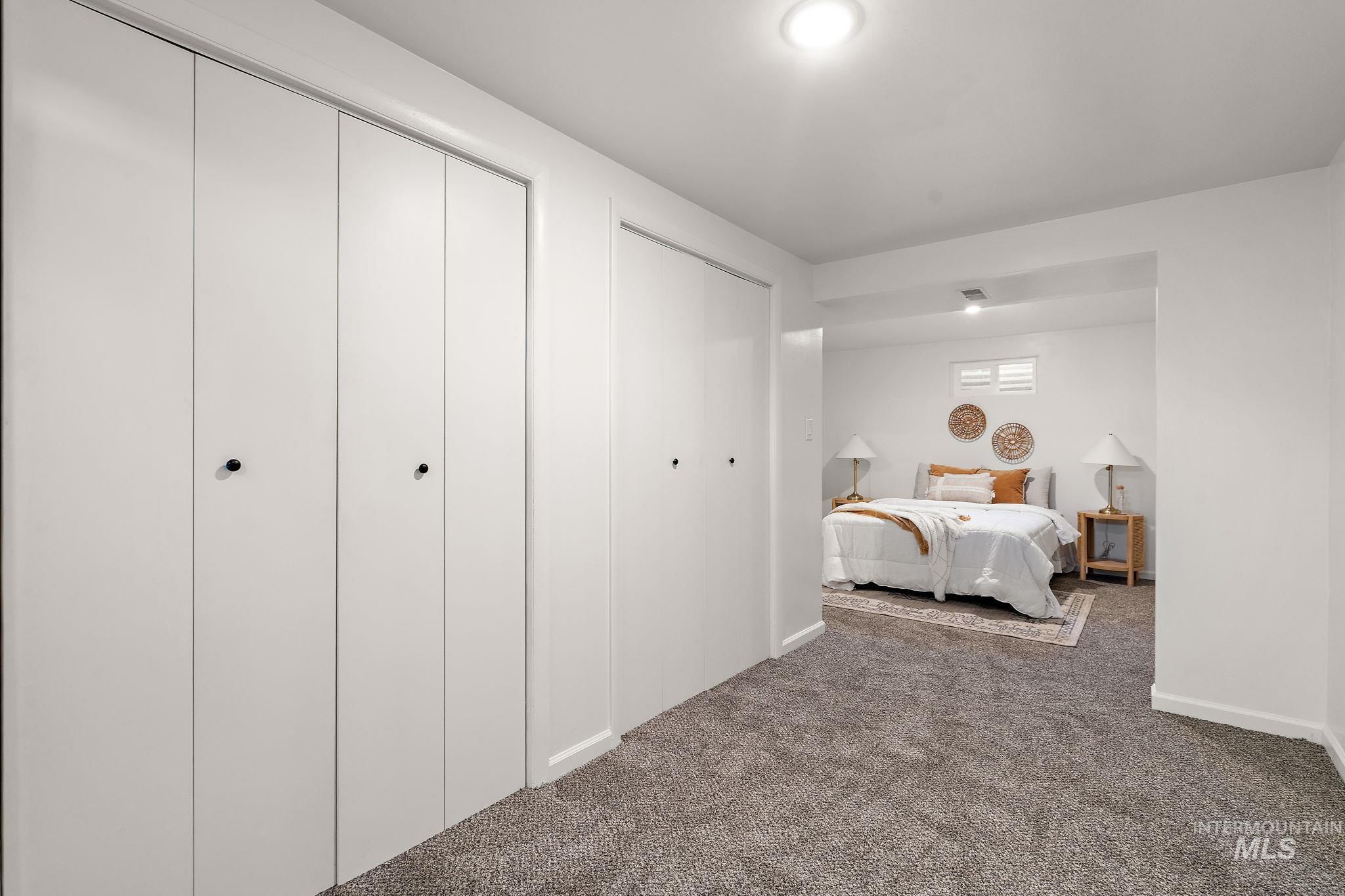 Carpeted bedroom with two closets and baseboards