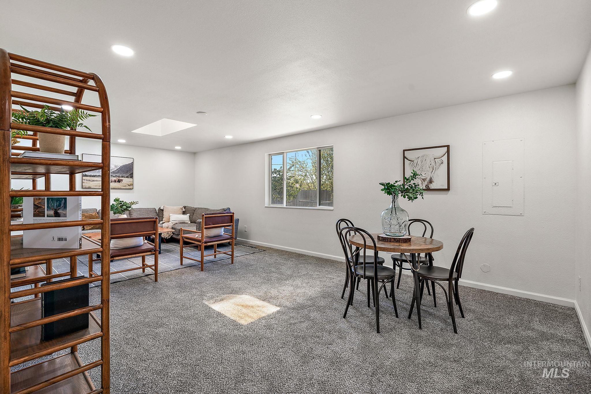 Carpeted dining room with a skylight, electric panel, and recessed lighting