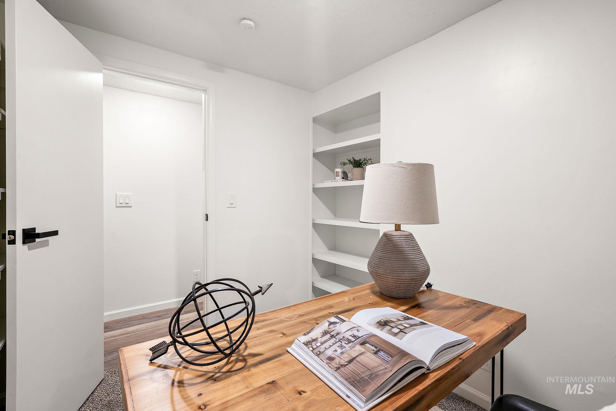 Office area featuring built in shelves and light wood-style floors