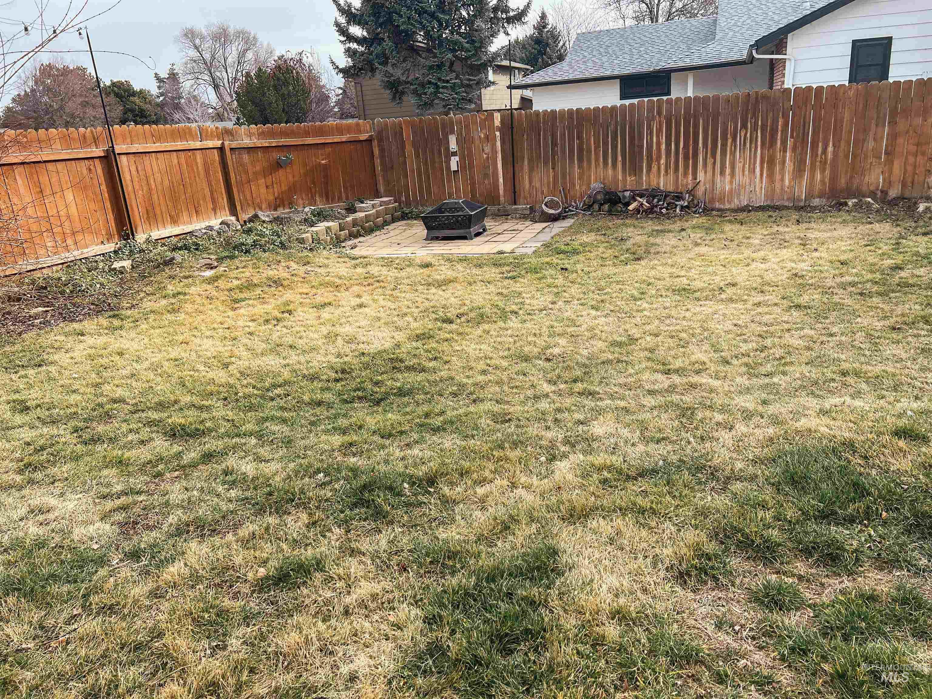 Fenced backyard with a fire pit and a patio area