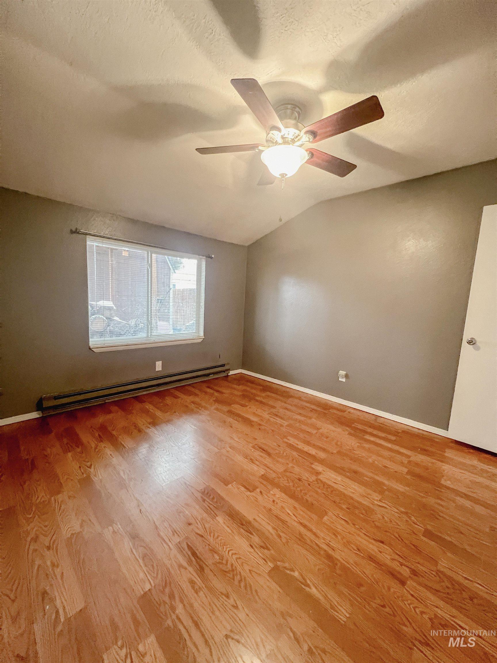 Spare room with a baseboard radiator, light wood-style flooring, and ceiling fan