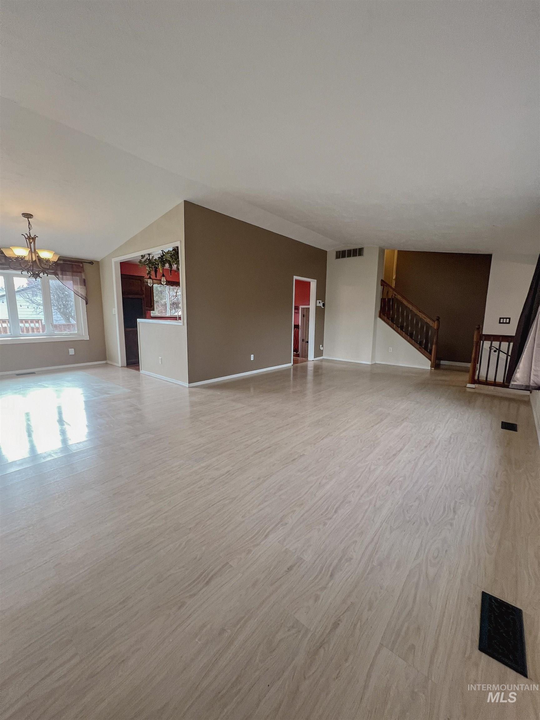 Unfurnished living room featuring suspended lighting and light wood-style floors