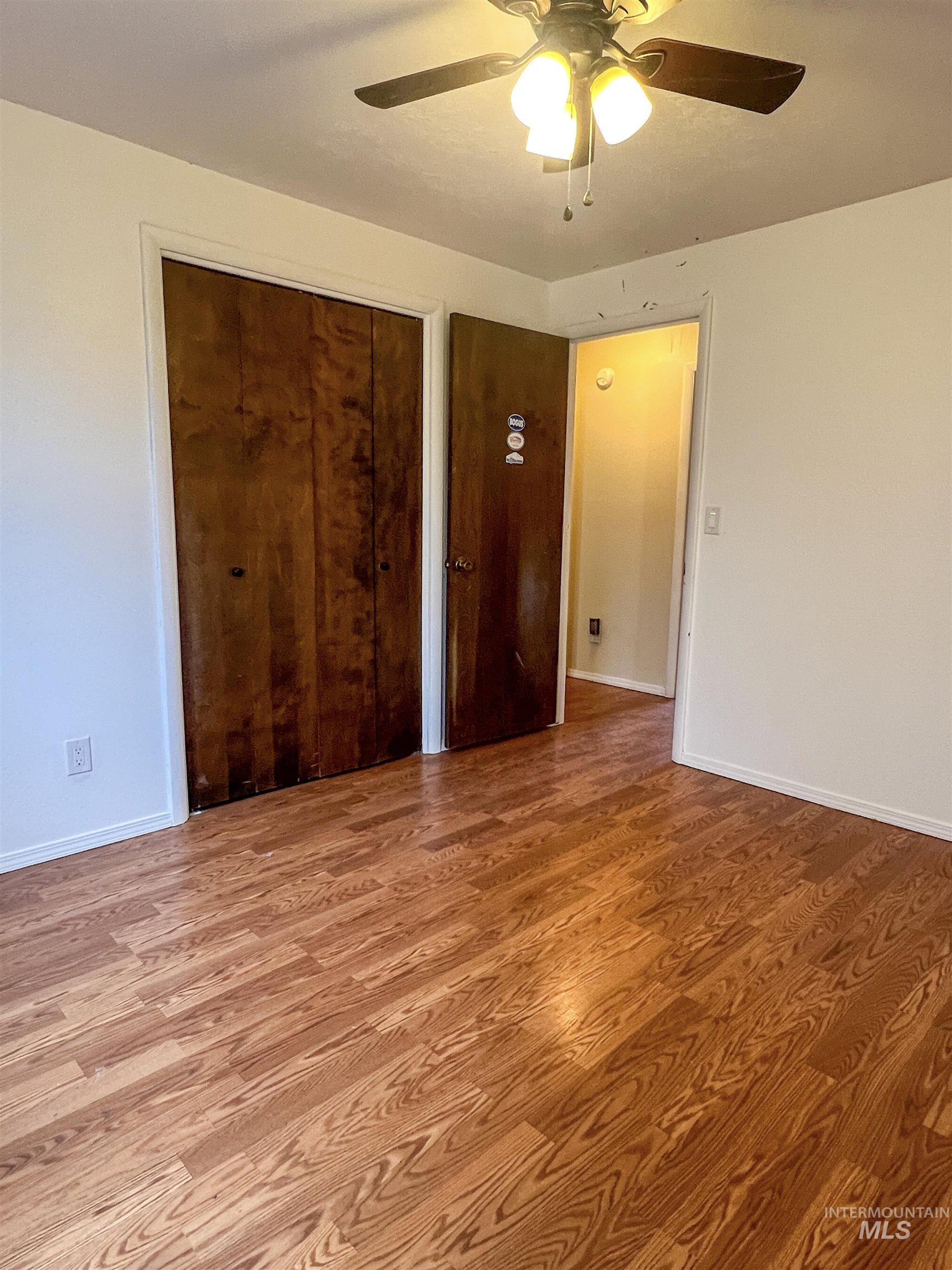 Unfurnished bedroom with a closet, wood finished floors, and a ceiling fan