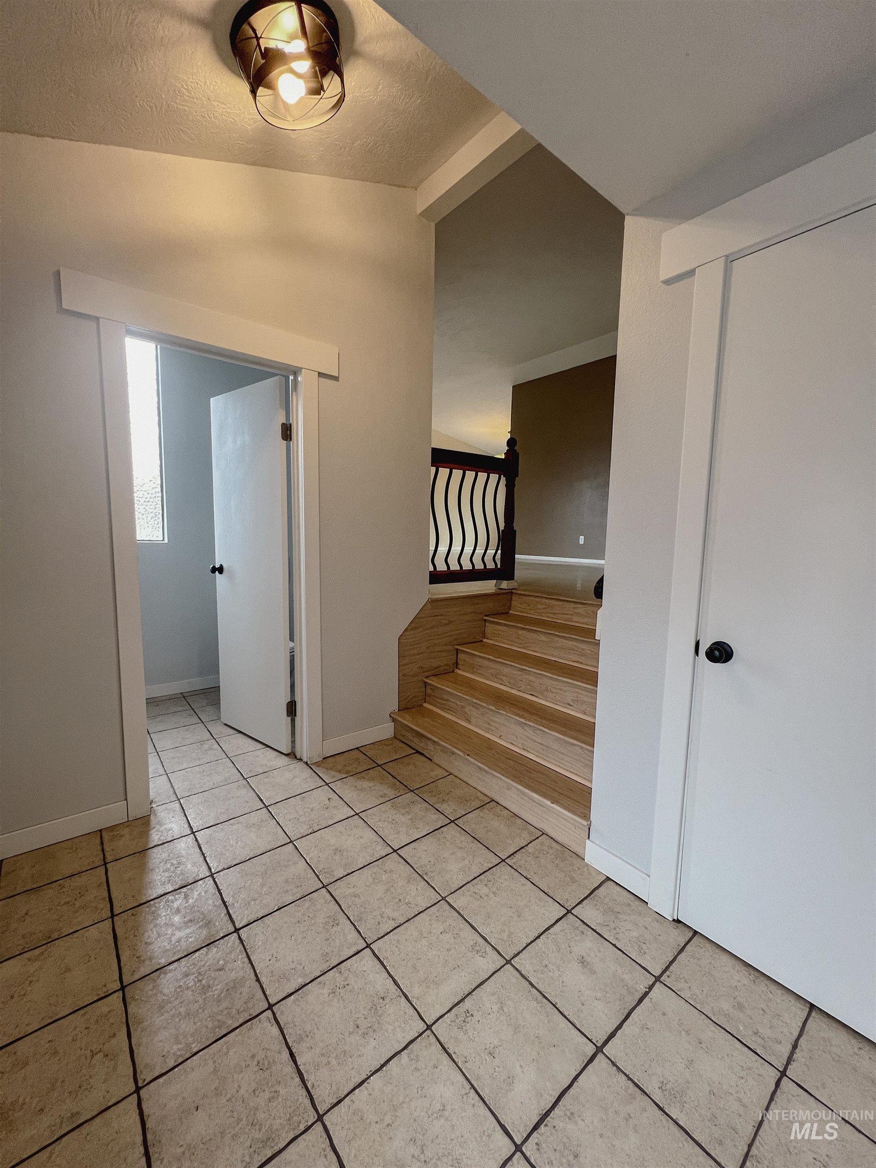 Foyer entrance with light tile patterned floors and a textured ceiling