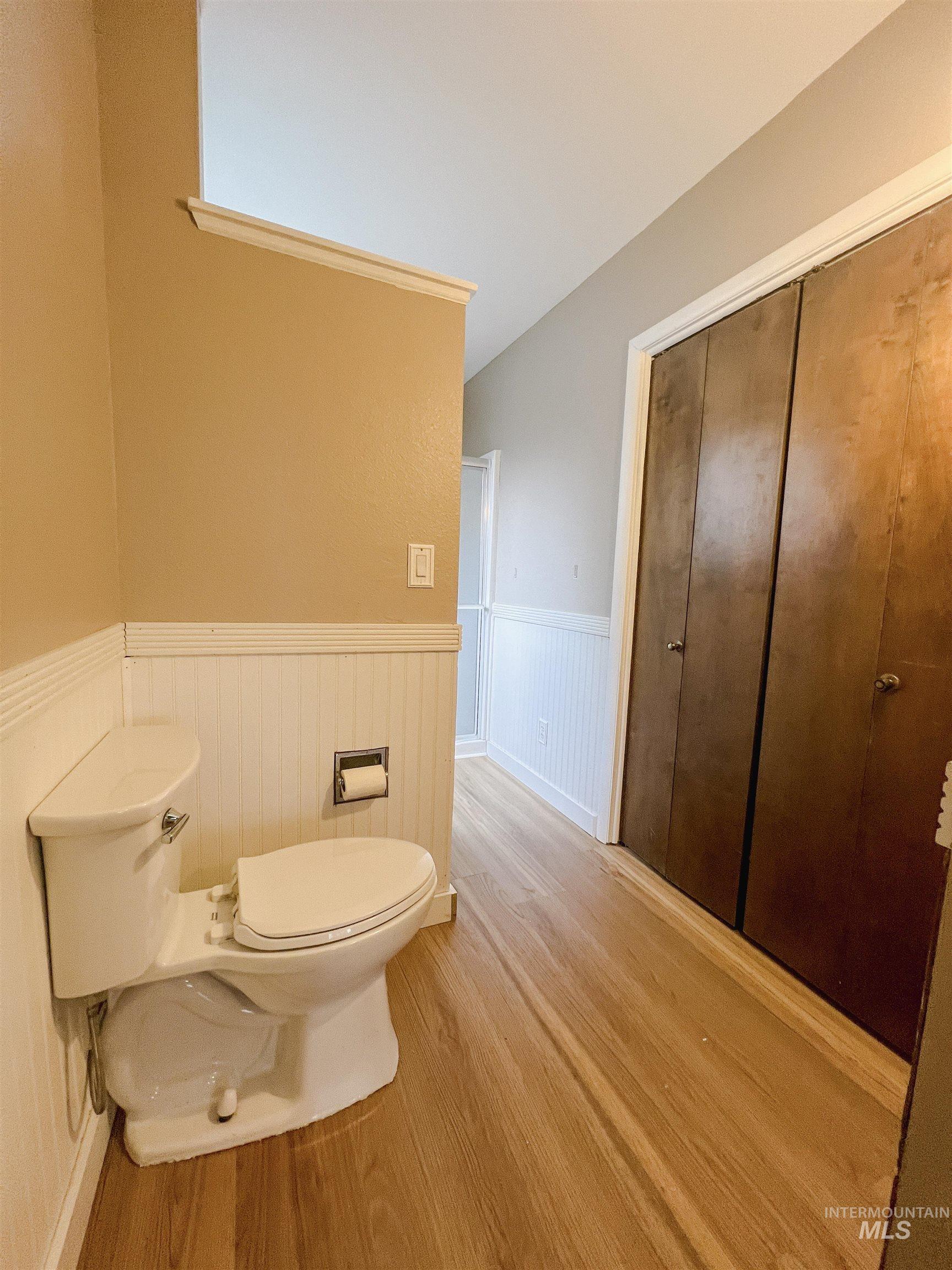 Bathroom featuring wainscoting, light wood finished floors, and a shower