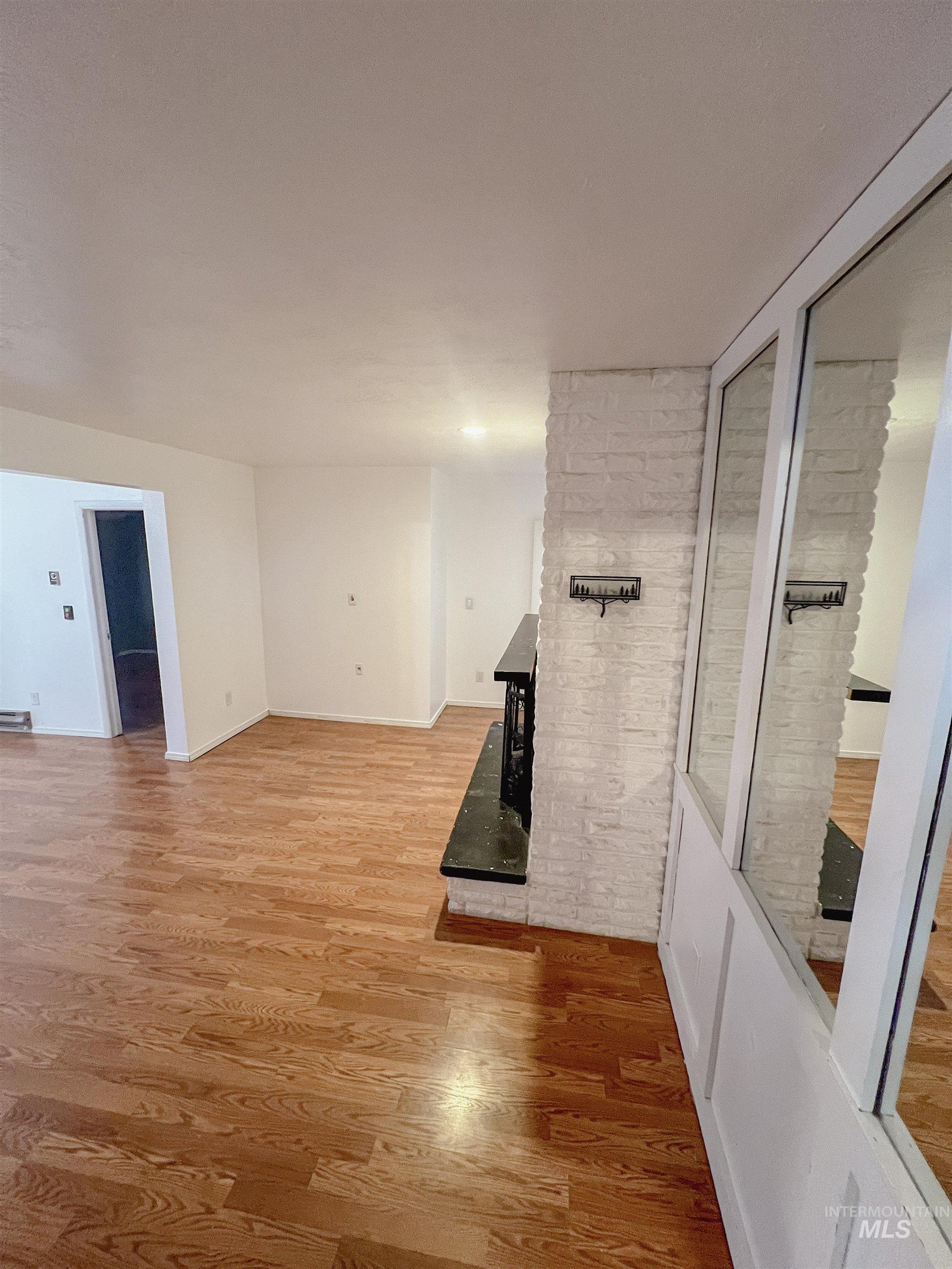 Unfurnished living room featuring light wood-style flooring and baseboards