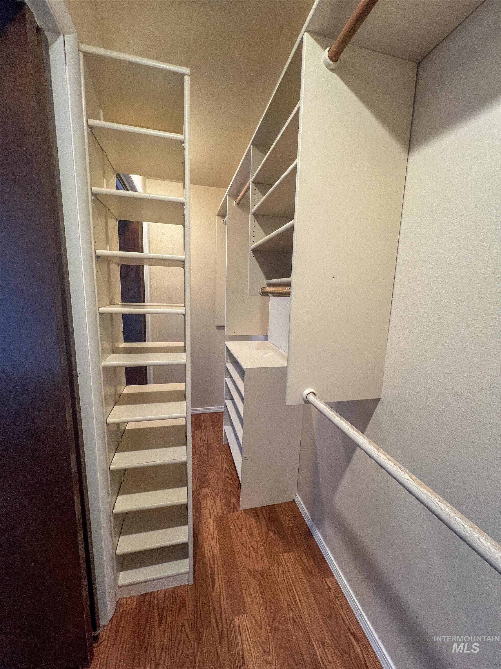 Walk in closet with dark wood-style flooring