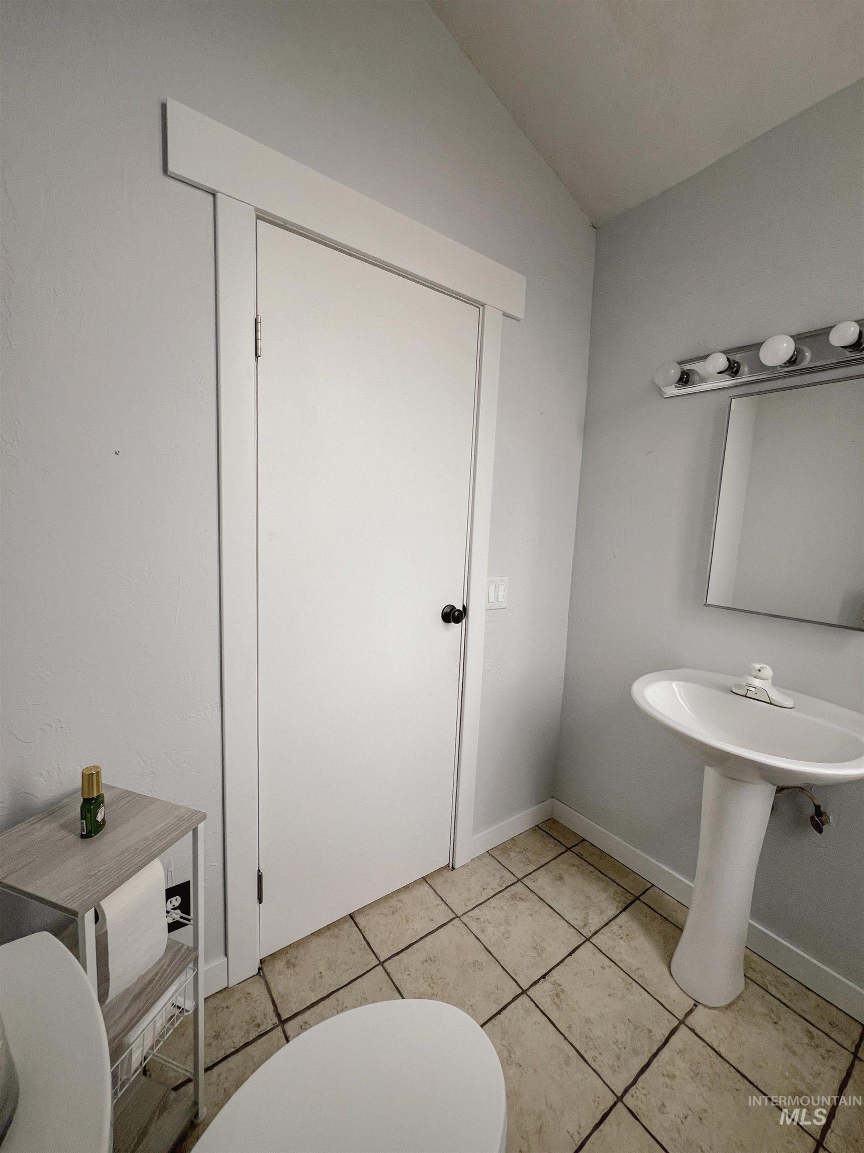 Half bath with lofted ceiling and light tile patterned floors