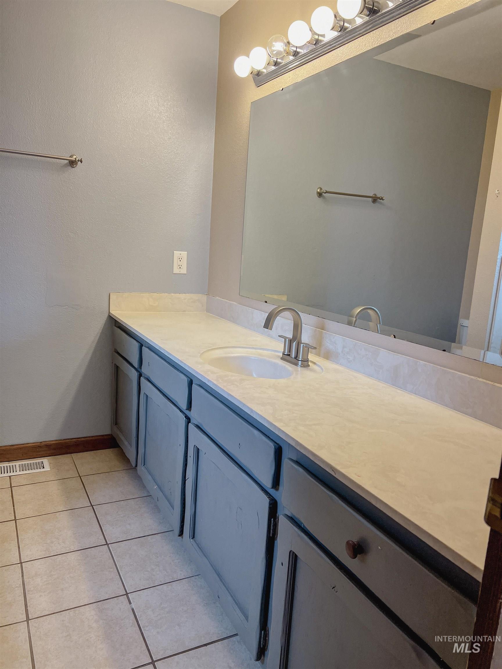 Bathroom featuring vanity, light tile patterned floors, and a textured wall
