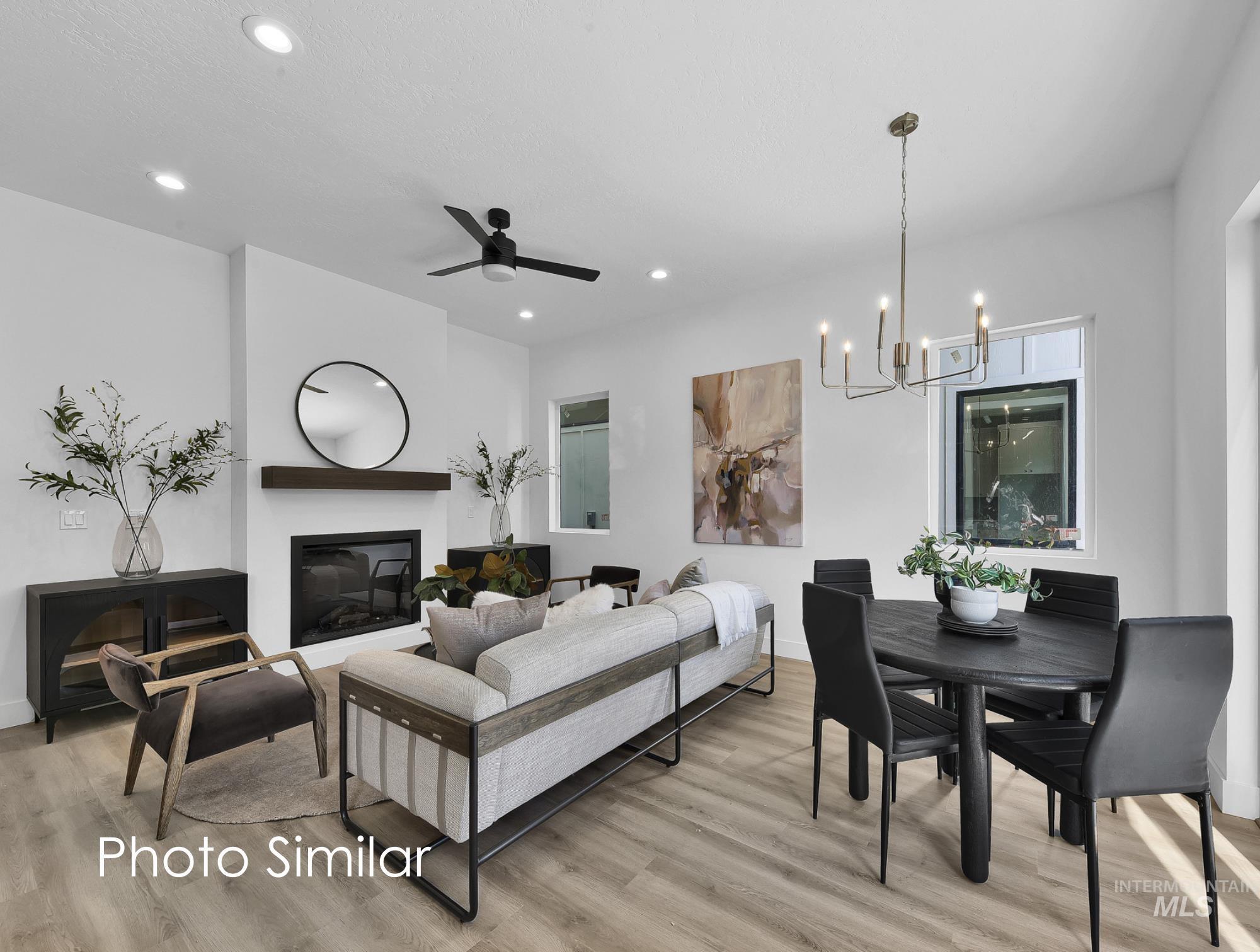 Living room with a ceiling fan, light wood-style floors, a glass covered fireplace, and suspended lighting