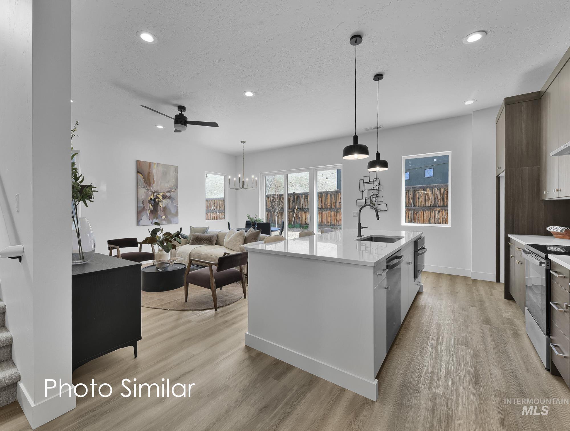Two tone kitchen featuring modern cabinets, light stone counters, light wood-style floors, a chandelier, and dual tone cabinetry
