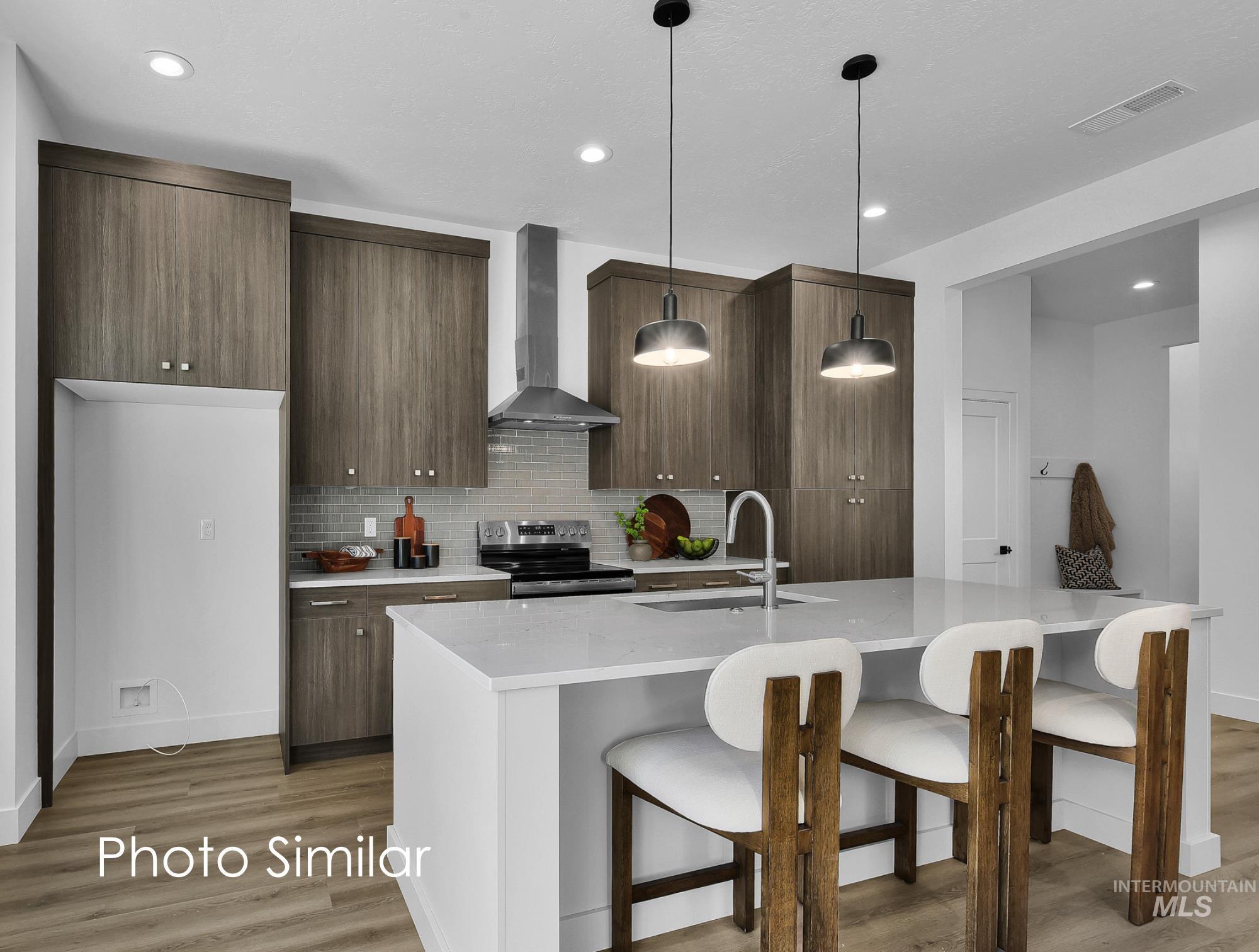Kitchen featuring a breakfast bar, modern cabinets, a center island with sink, light stone countertops, and hanging light fixtures