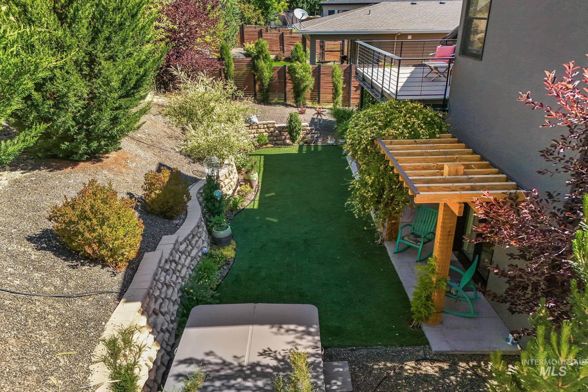 Expansive backyard featuring artificial turf, tiered retaining walls, and established shrubbery