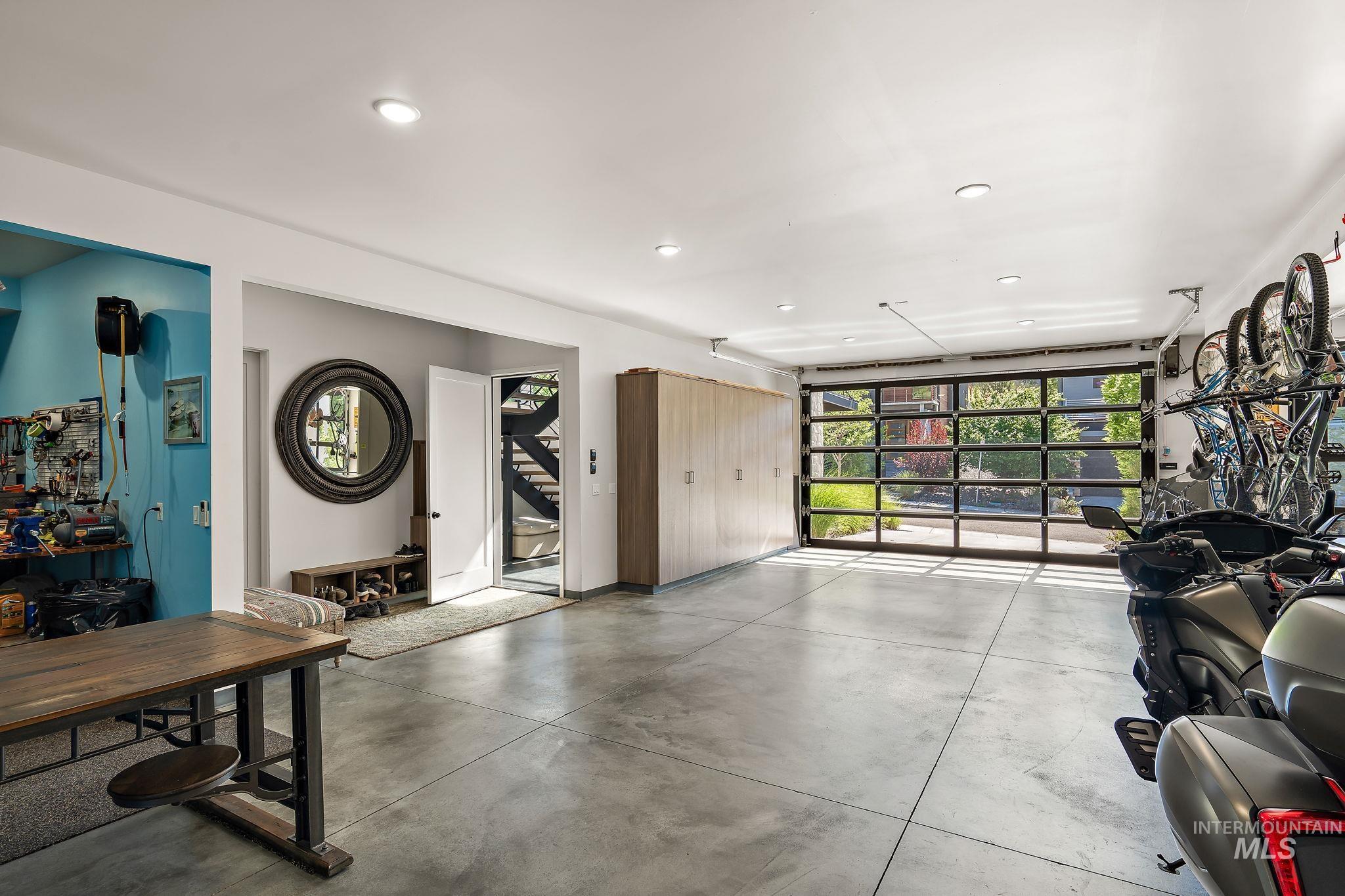 Spacious garage with a full-view garage door, polished concrete flooring, recessed lighting, and integrated storage cabinetry