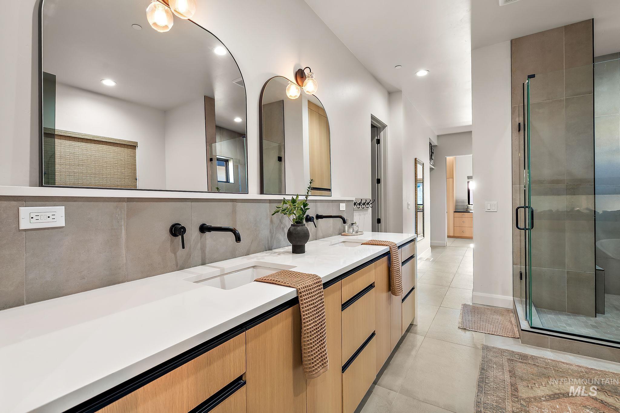 Dual sink vanity with light wood-finish cabinetry, white countertops, and matte black wall-mounted faucets