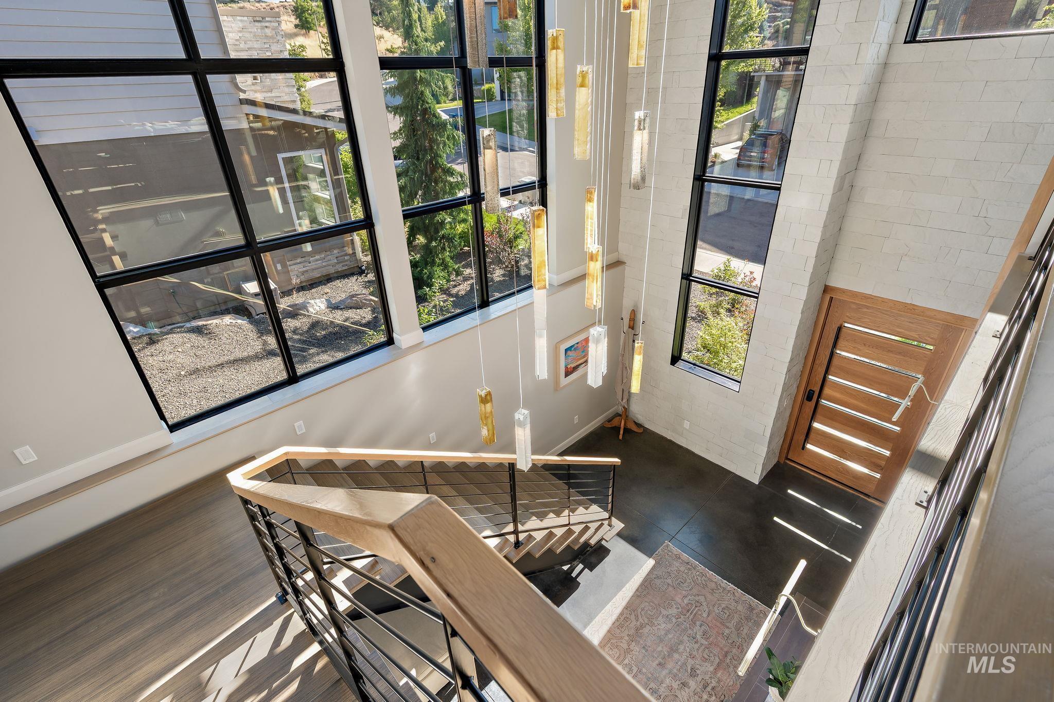 Two-story entry featuring expansive black-framed windows, a multi-tiered chandelier, and a solid wood entry door
