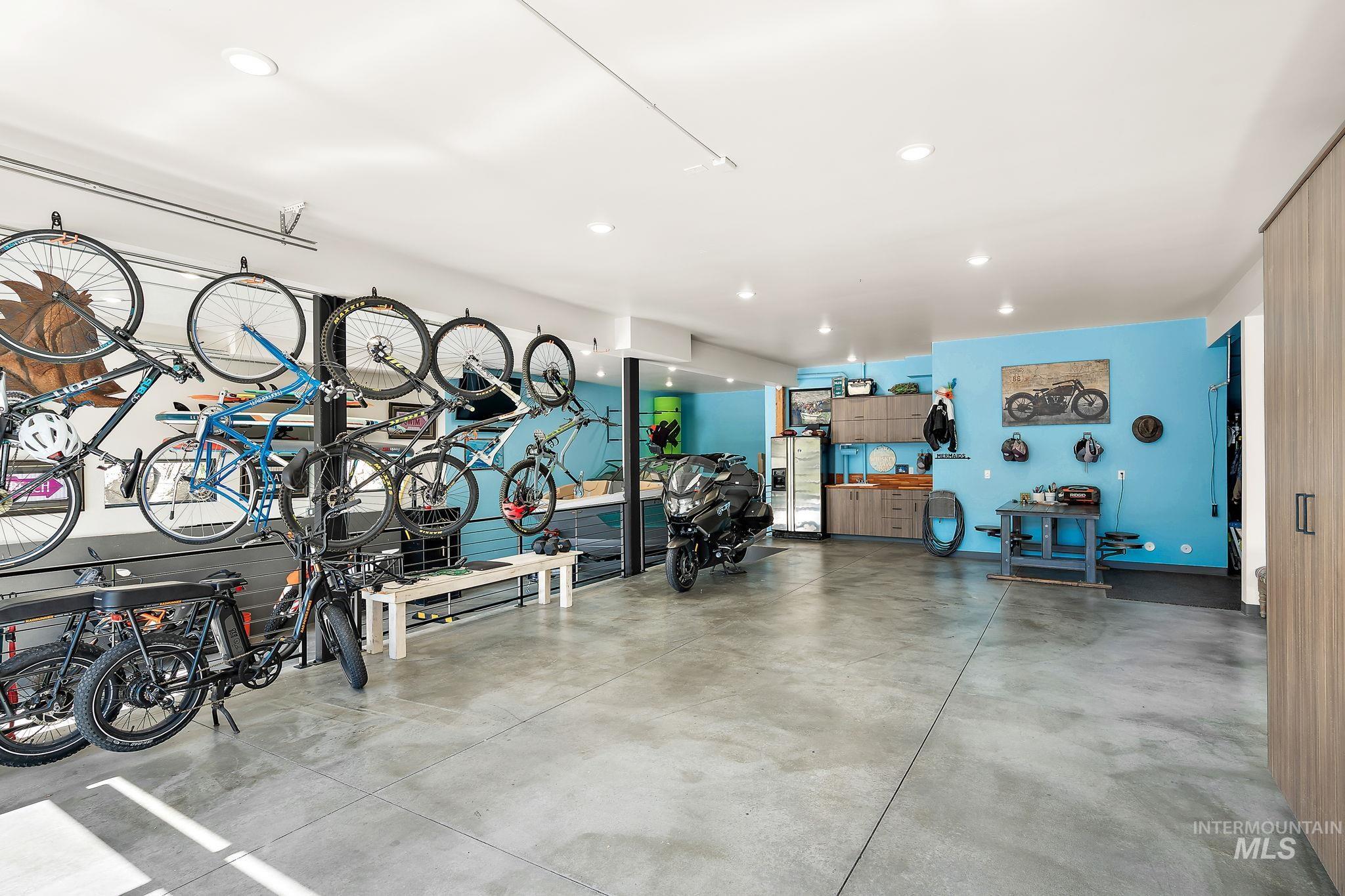 Spacious garage featuring concrete flooring, track lighting, built-in cabinetry, and integrated shelving
