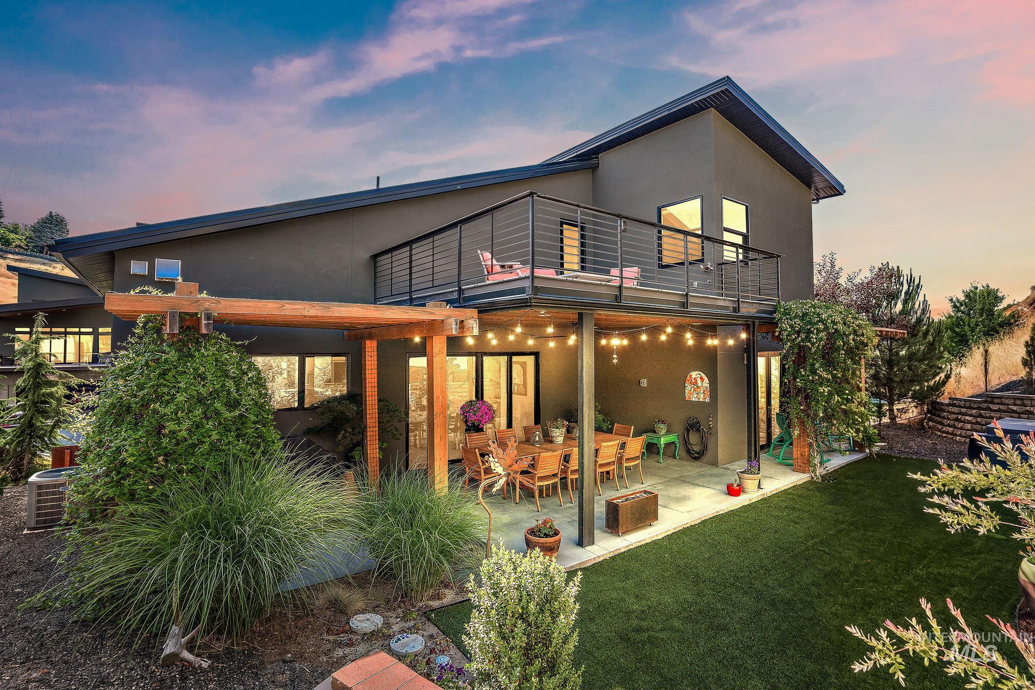 Modern architecture featuring dark-toned stucco siding and a covered patio with string lighting