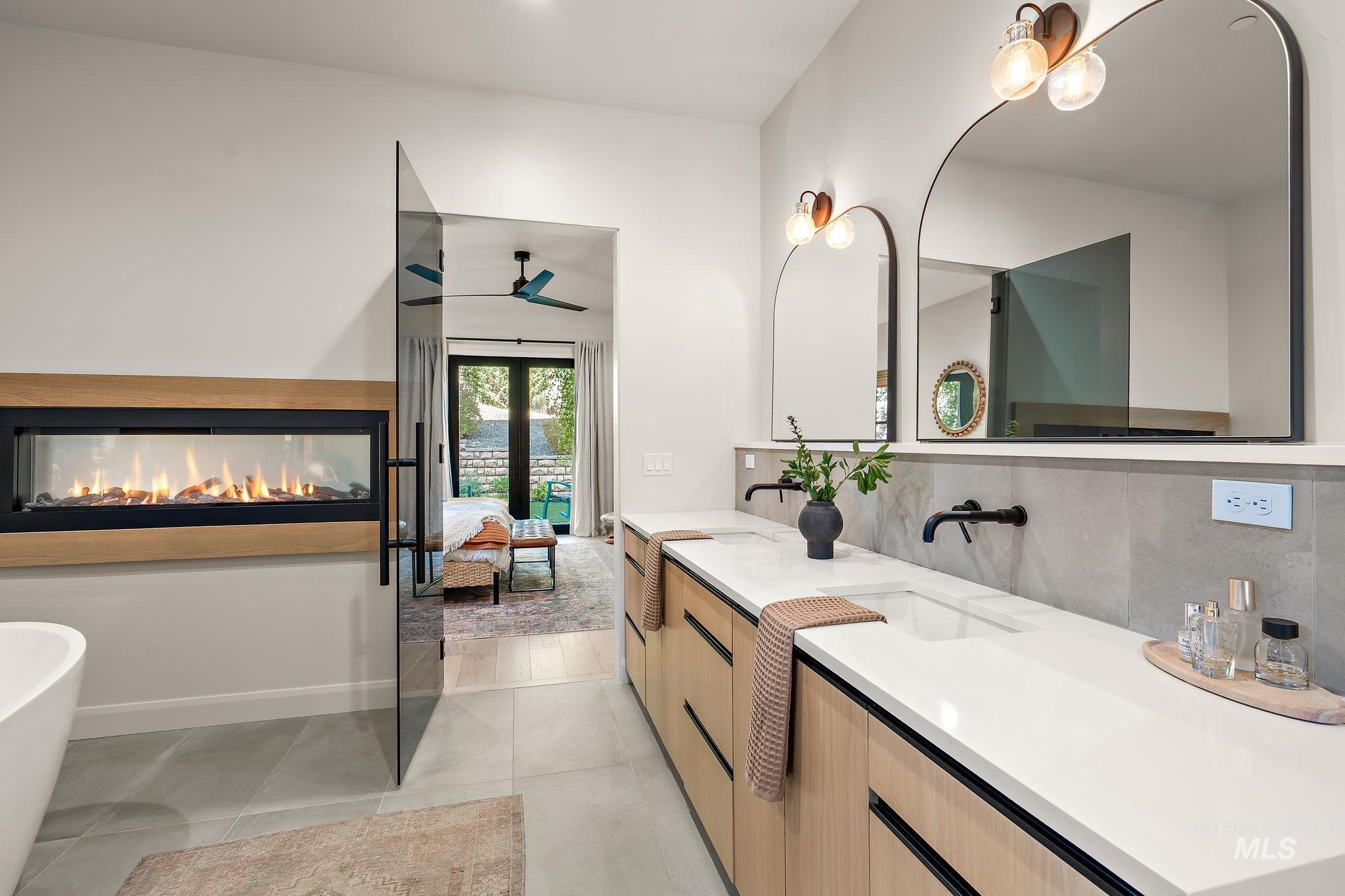 Dual arched mirrors and sconce lighting above a double vanity with integrated sinks, quartz countertops, and matte black wall-mounted faucets