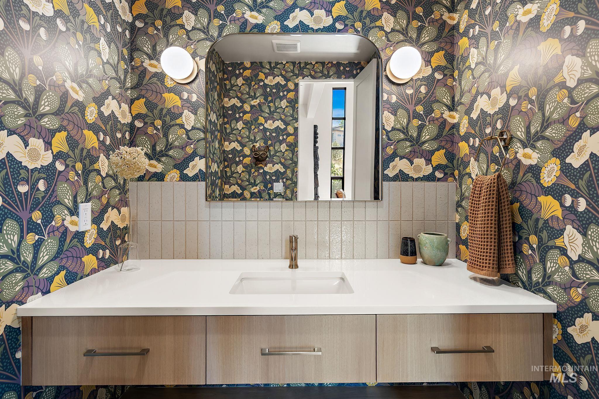 Vanity featuring a white countertop with an integrated rectangular sink, set against a floral wallpaper backdrop