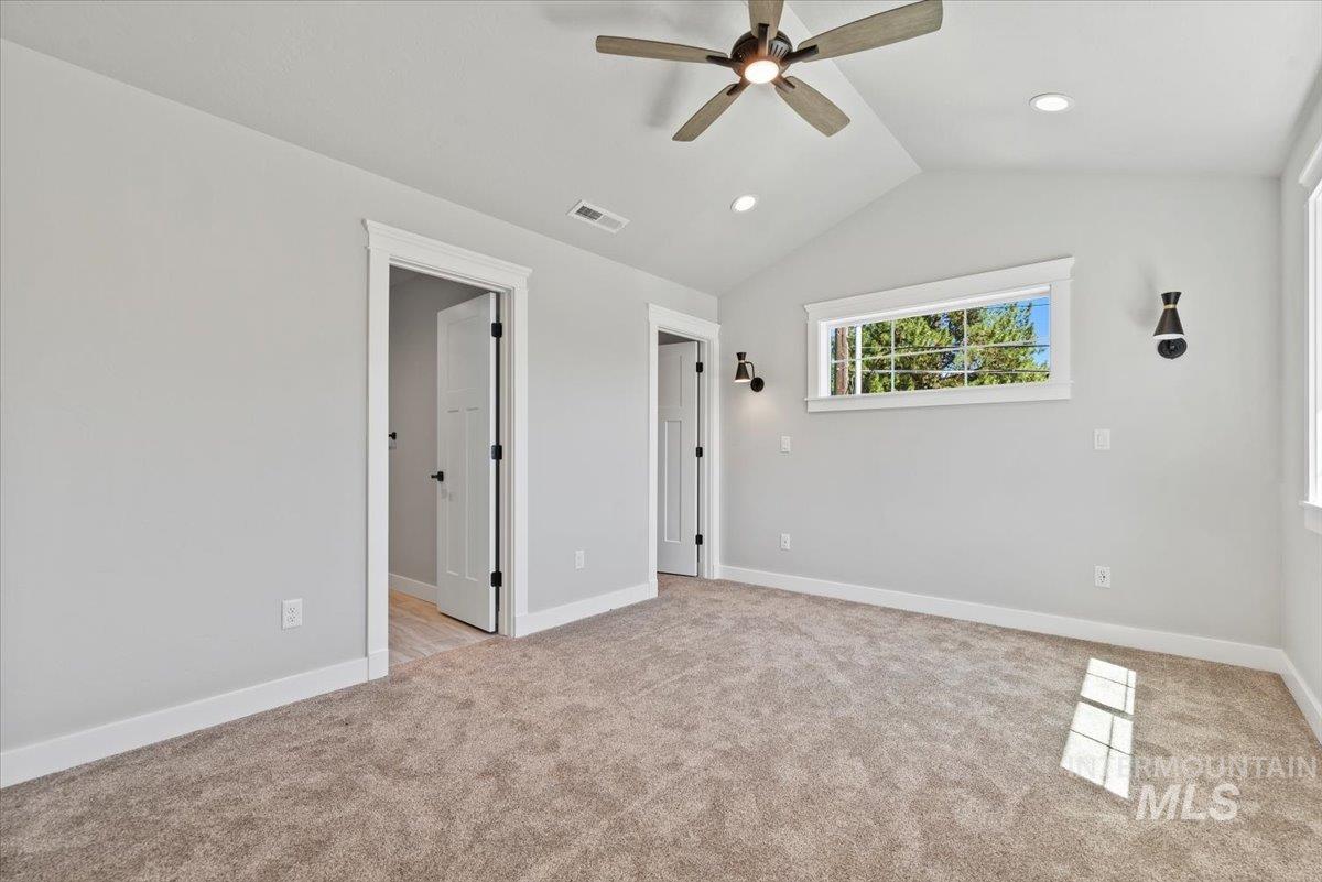 Primary bedroom with light carpet, vaulted ceiling, recessed lighting, and ceiling fan