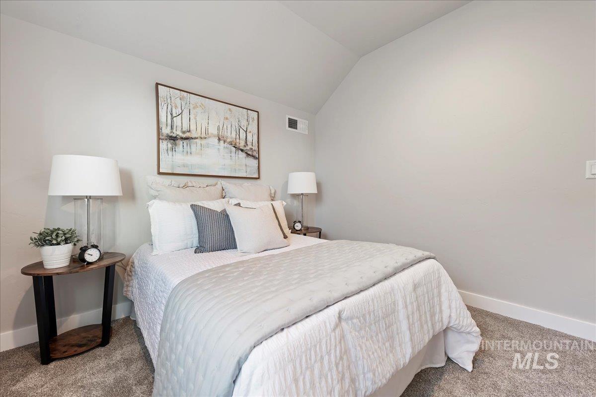 Carpeted bedroom featuring vaulted ceiling and baseboards
