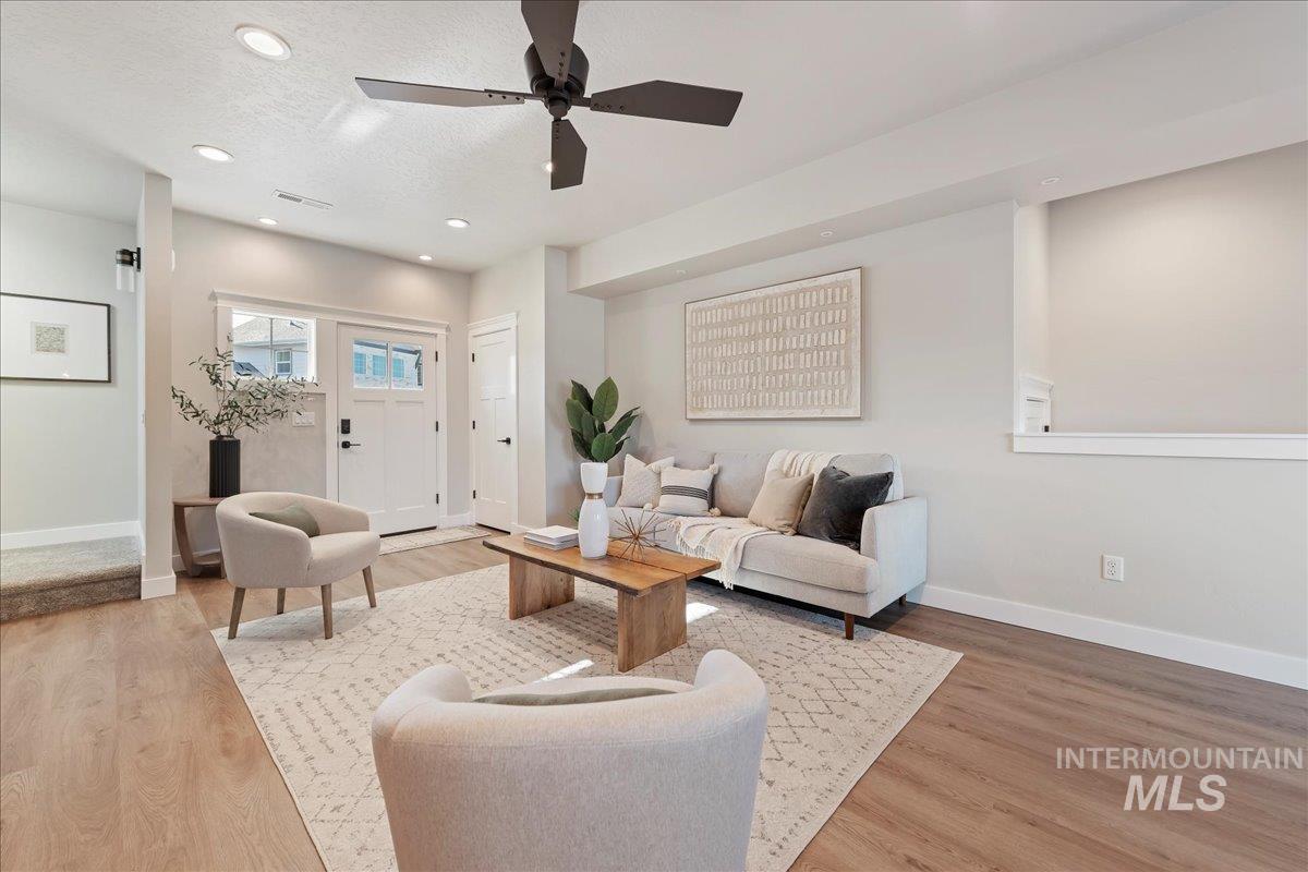 Living room with ceiling fan, light wood-type flooring, recessed lighting, and a textured ceiling