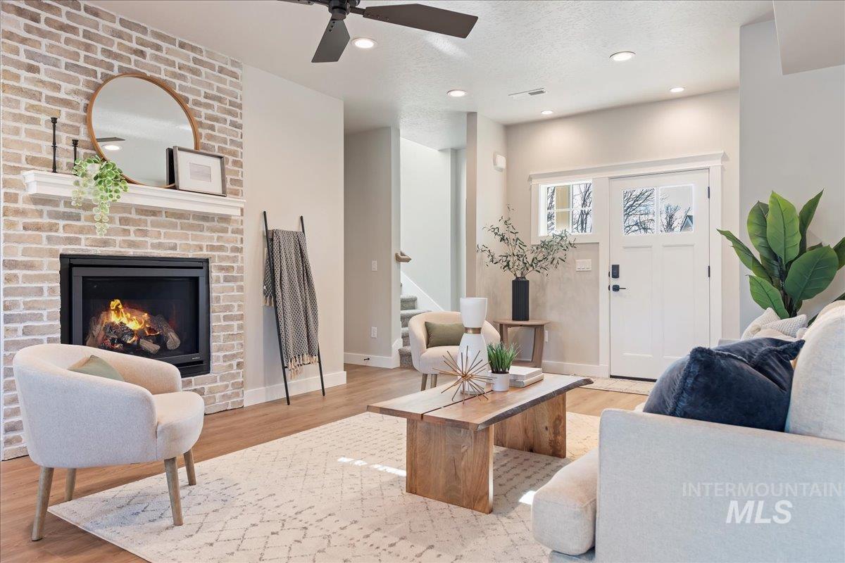 Living room with a fireplace, light wood-type flooring, a textured ceiling, stairway, and recessed lighting