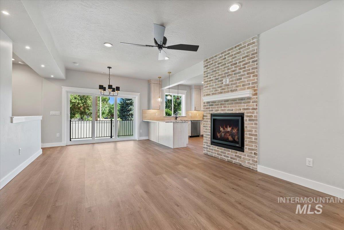 Unfurnished living room with light wood-style floors, a chandelier, ceiling fan, recessed lighting, and a fireplace