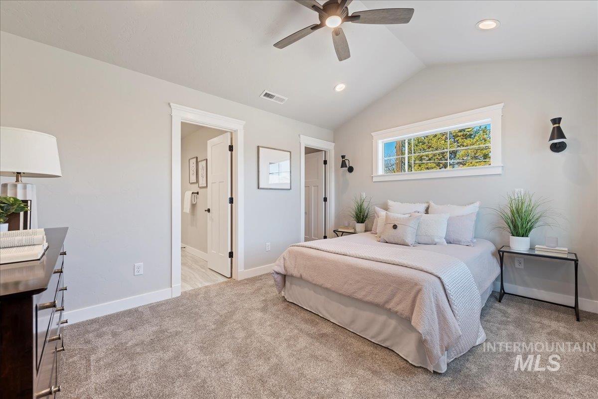 Bedroom featuring vaulted ceiling, light carpet, a ceiling fan, and ensuite bathroom