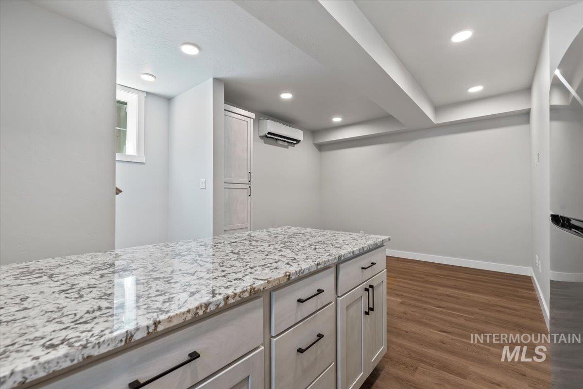 ADU featuring a wall unit AC, light wood LVP floors, light stone countertops, recessed lighting, and freestanding refrigerator