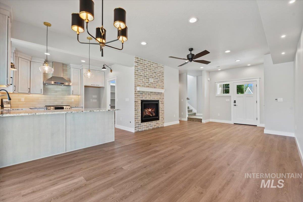 Unfurnished living room featuring stairway, recessed lighting, light wood-type flooring, a fireplace, and a ceiling fan
