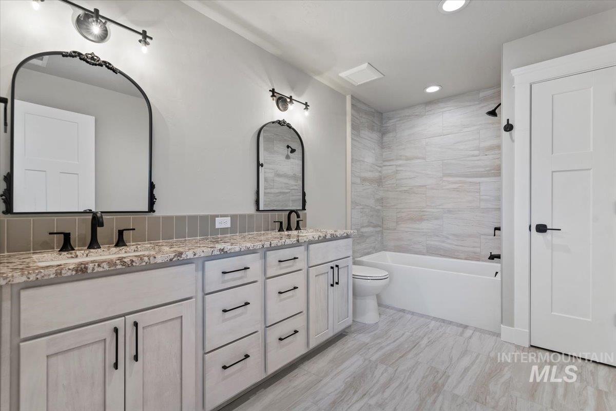 Full bathroom featuring double vanity, recessed lighting, and tub / shower combination