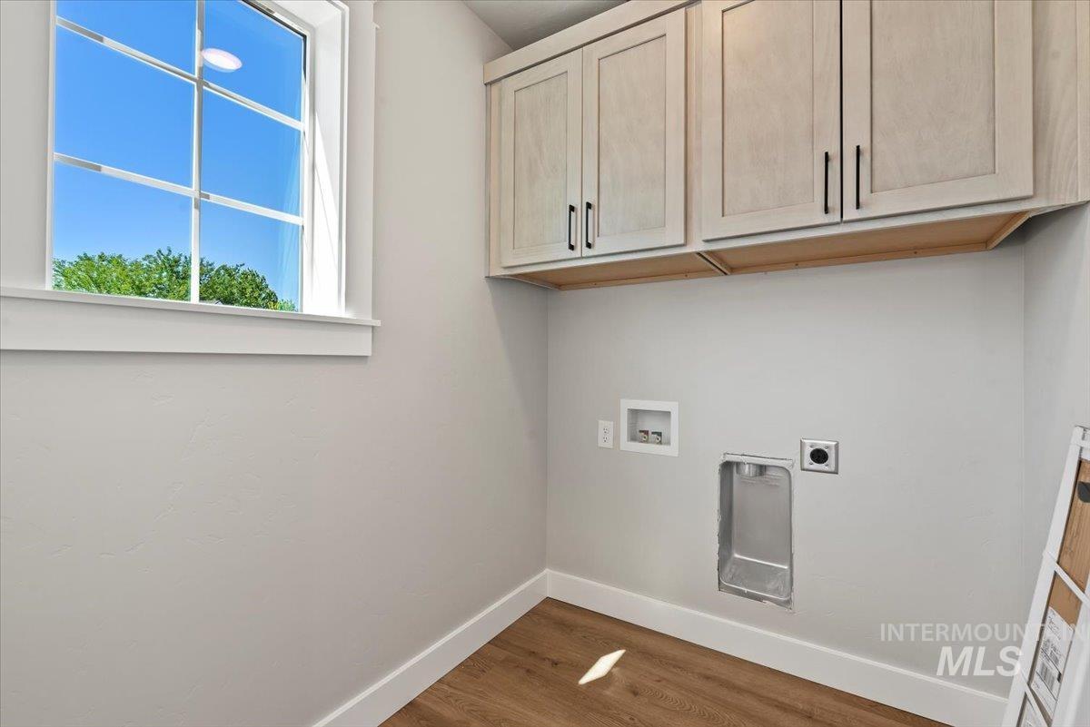 Laundry room featuring cabinet space, electric dryer hookup, hookup for a washing machine, and wood finished floors