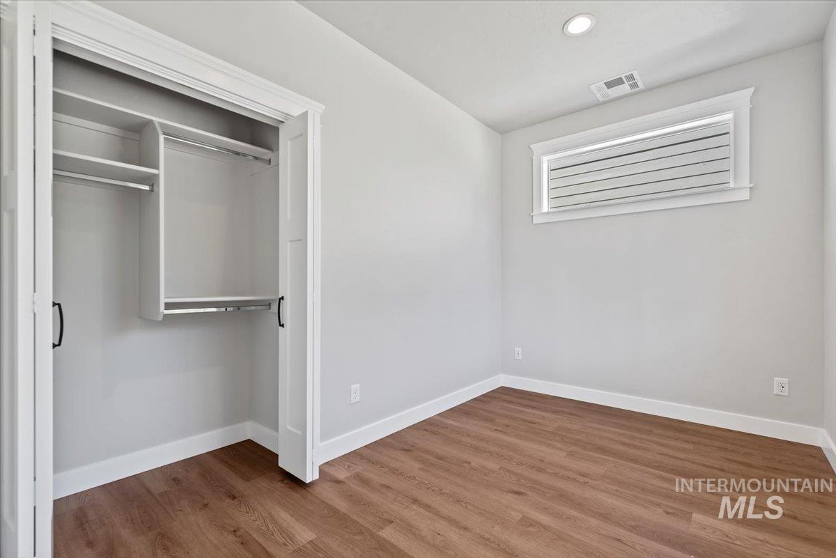 Unfurnished bedroom featuring wood finished floors, a closet, and recessed lighting