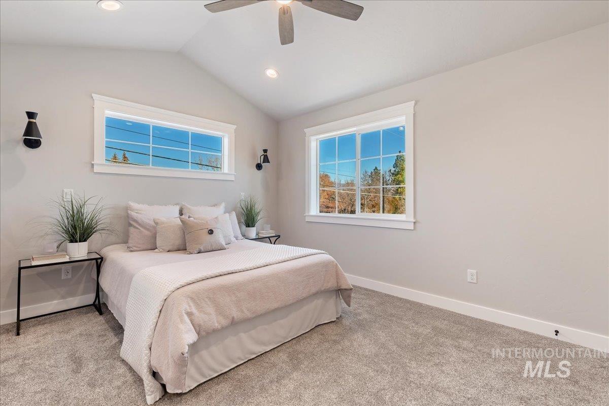Carpeted bedroom with lofted ceiling and ceiling fan