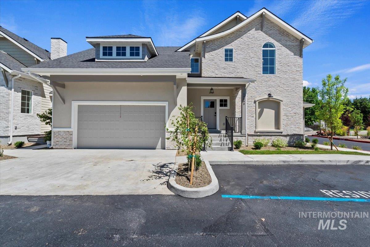View of front of property with a chimney, concrete driveway, brick siding, an attached garage, and stucco siding