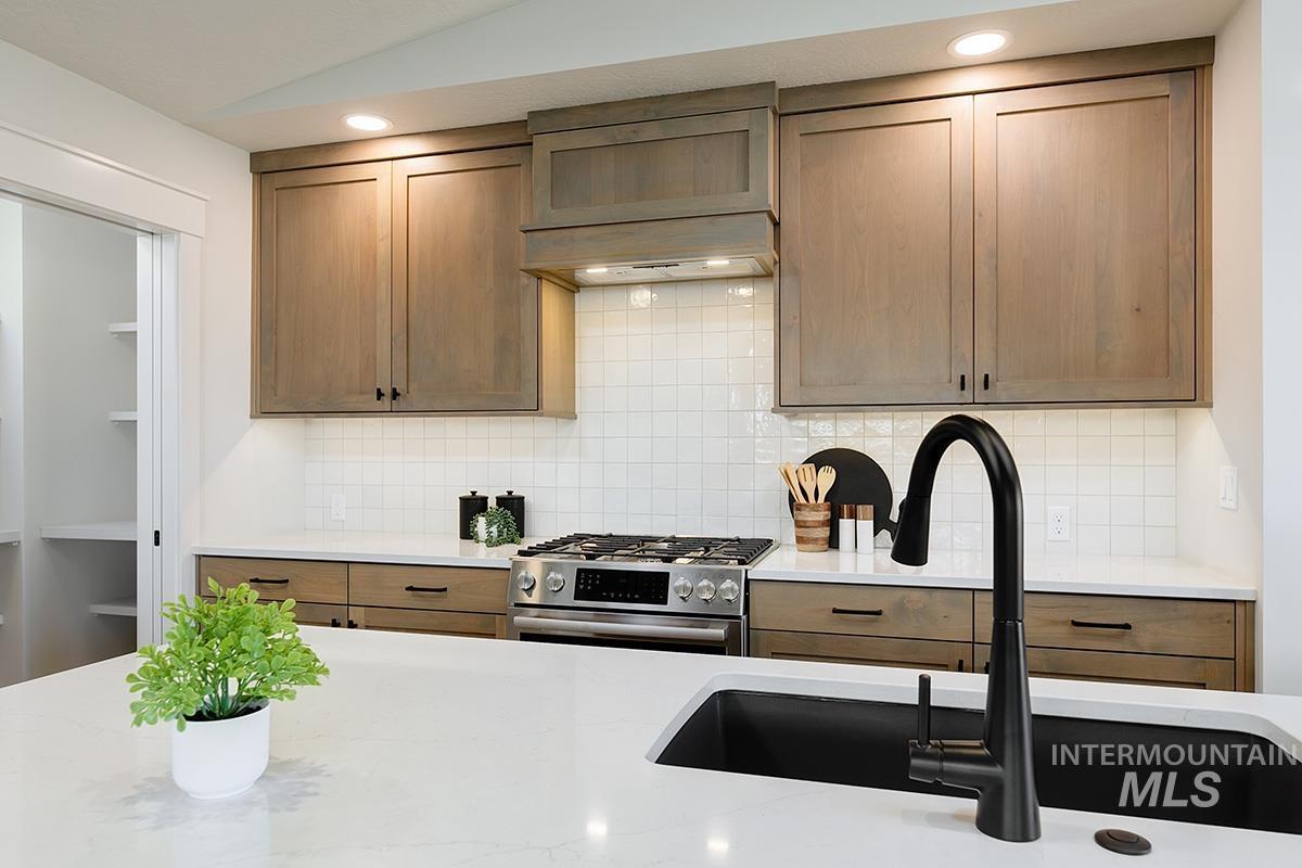 Contemporary kitchen featuring light wood-finish cabinetry, white square tile backsplash, and stainless steel appliances