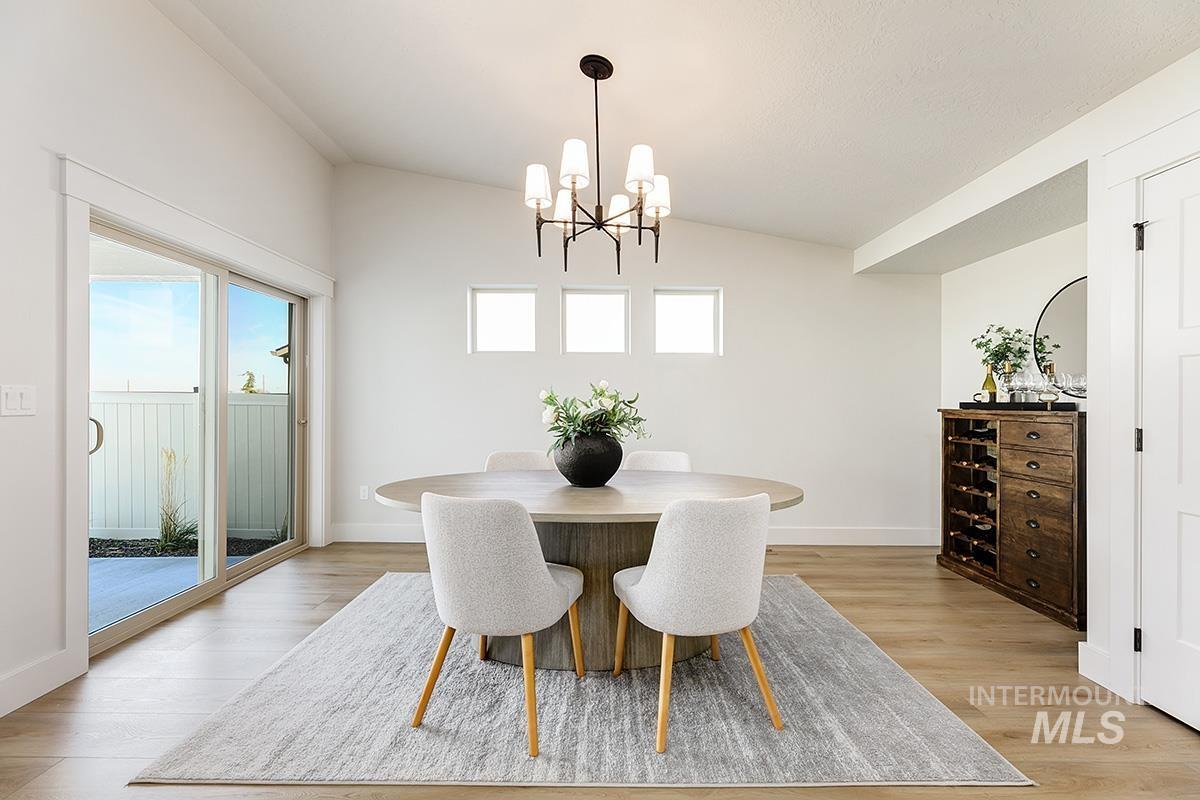 Vaulted ceiling dining area featuring light wood-finish flooring and a contemporary chandelier