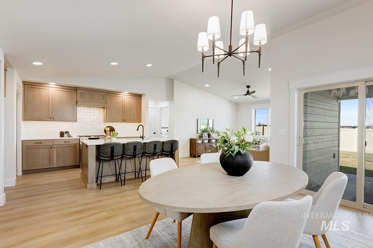 Open-concept dining area with wood-finish flooring, a contemporary chandelier, and direct access to the exterior through a glass slider