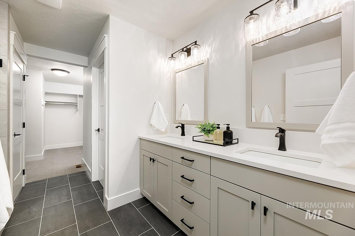 Double vanity with light gray cabinetry, white countertops, dual integrated sinks, and matte black fixtures