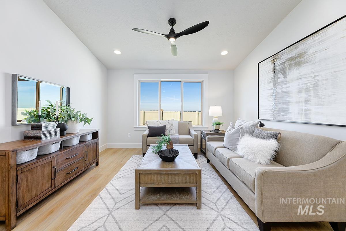 Bright living area featuring wood-finish flooring, recessed lighting, a modern ceiling fan, and a large window