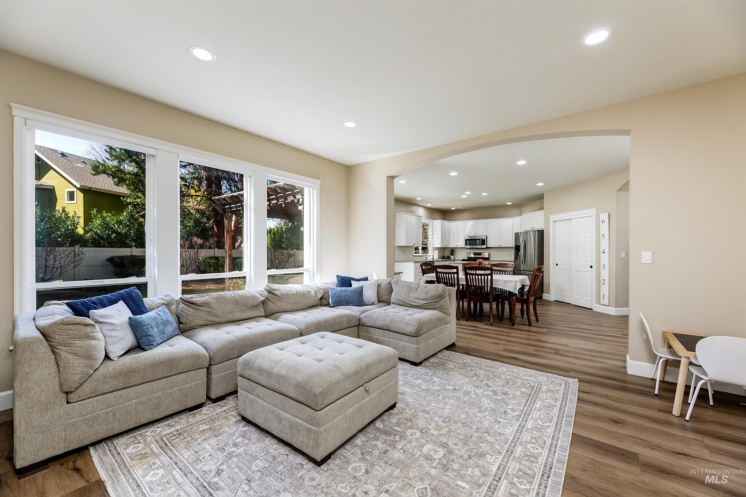 Living room with arched walkways, recessed lighting, and dark wood-style flooring