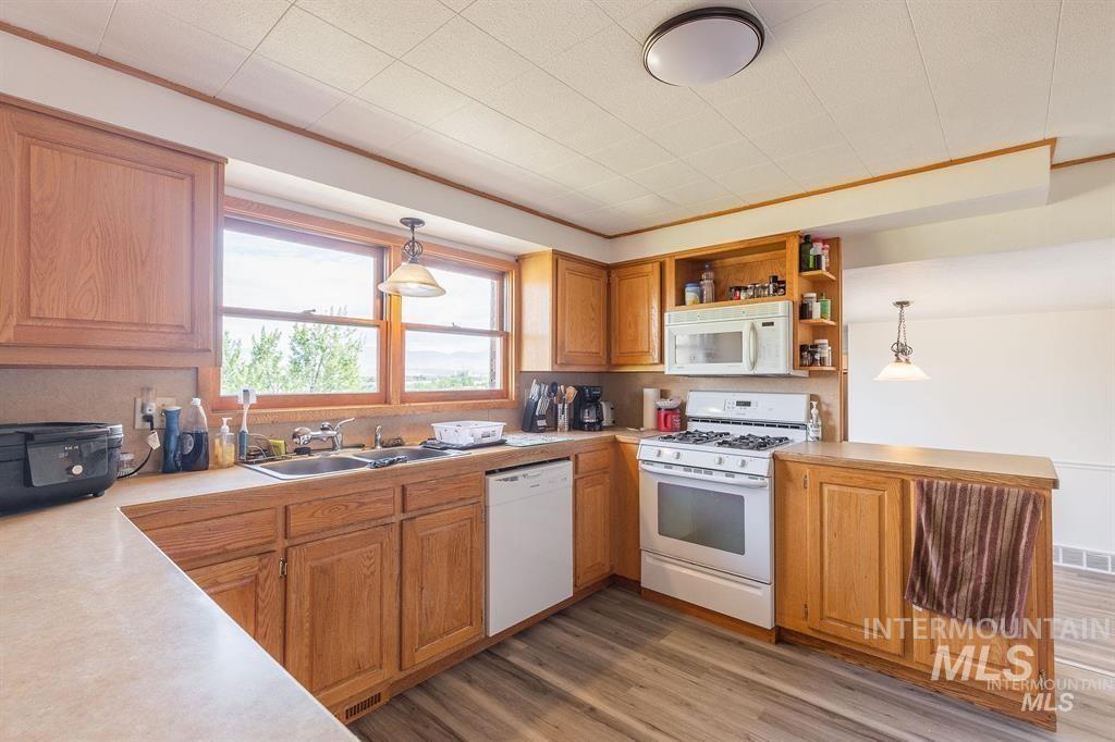 Kitchen with white appliances, light countertops, open shelves, a peninsula, and decorative light fixtures