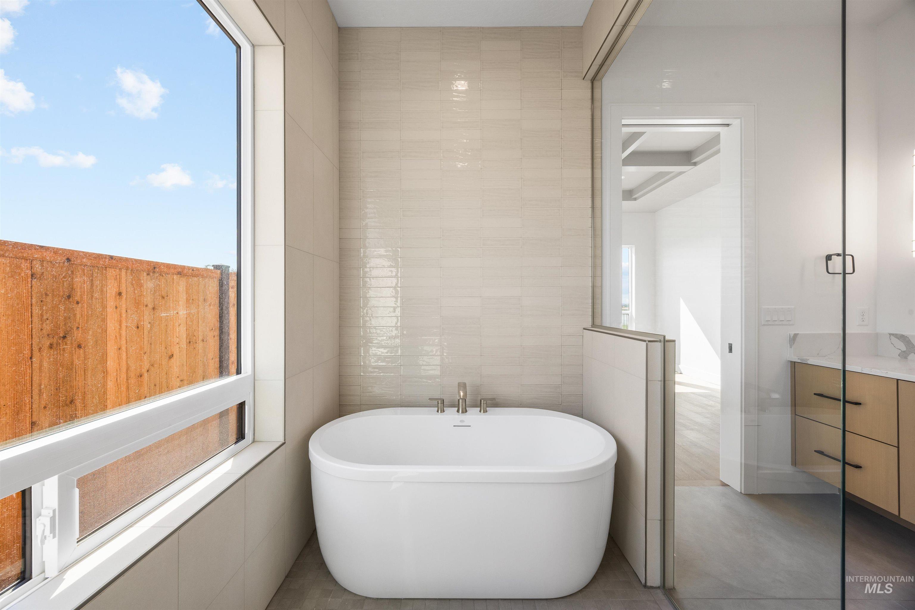 Bathroom featuring tile walls, vanity, and a freestanding bath