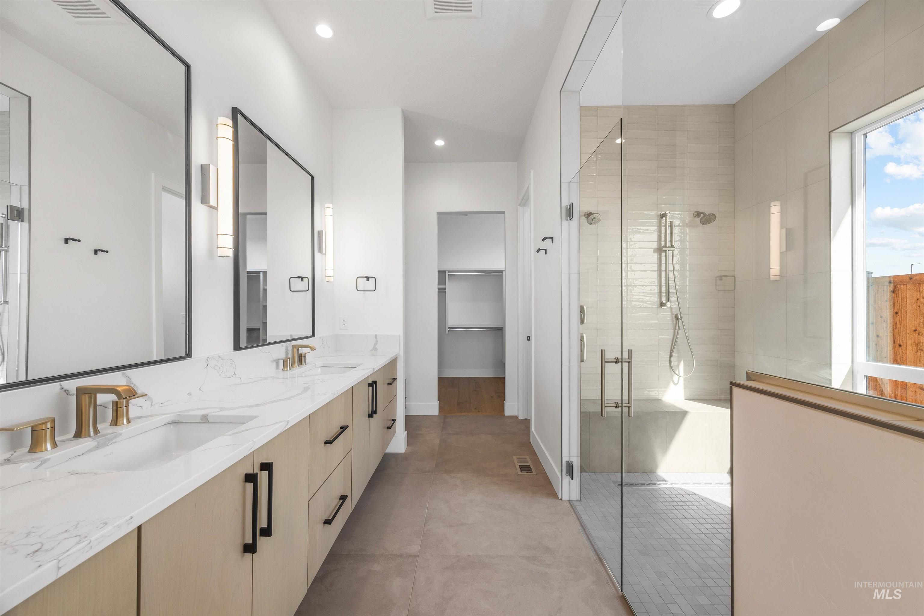 Full bathroom with a shower stall, double vanity, recessed lighting, light tile patterned floors, and a spacious closet